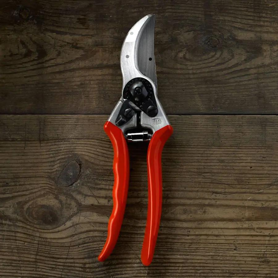 Pruning shears with red handles on a wooden surface