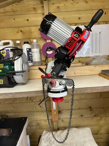 Chainsaw being sharpened on a machine clamped to a work top
