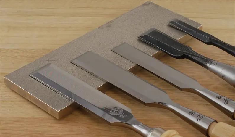 Set of metal chisels on a wooden surface