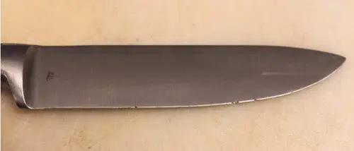 Knife blade with small damage to the bevel on a cream background