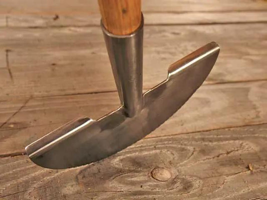 Metal garden hoe with wooden handle on a wooden surface