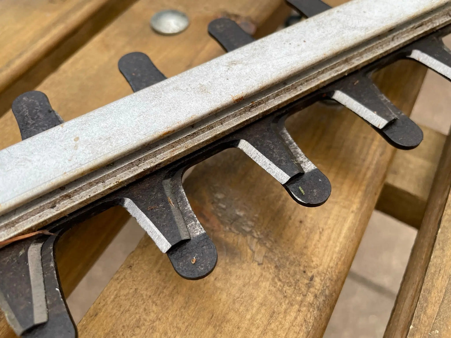 Close-up of a metal hedge trimmer with wooden background