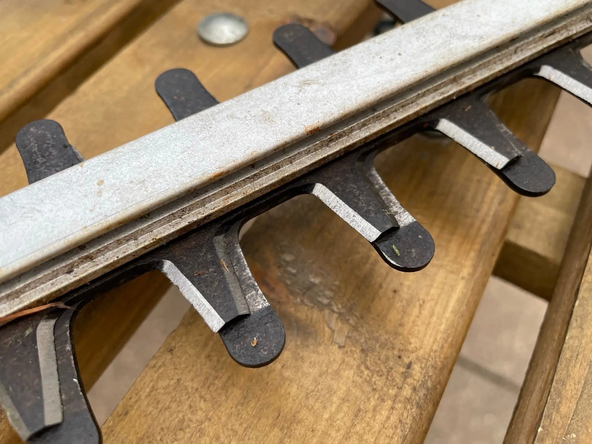 Close-up of a metal hedge trimmer with wooden background